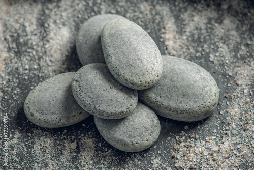 Natural soap in the shape of stones on a black background covered with sea salt. Concept of organic cosmetics and spa treatments