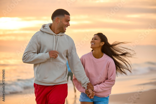 Close Up Of Couple In Casual Clothing On Vacation Holding Hands Running Along Beach Shore At Dawn
