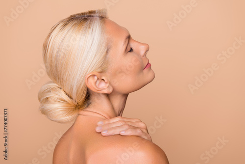 Photo of adorable sweet woman naked shoulders applying body cream empty space isolated beige color background