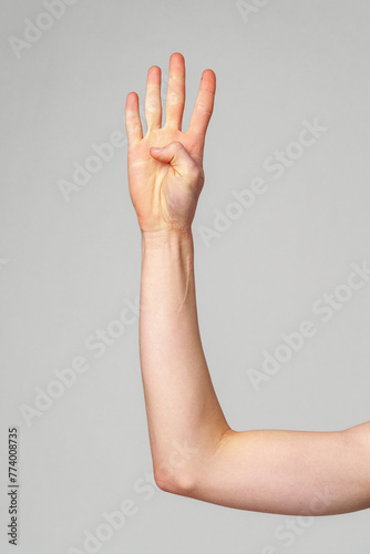 Raised Human Hand Displaying Four Fingers Against a Neutral Background