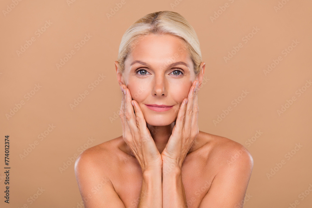 Photo of adorable pretty woman naked hands arms cheeks cheekbones using face cream isolated beige color background Photo of adorable pretty woman naked hands arms cheeks cheekbones using face cream isolated beige color background