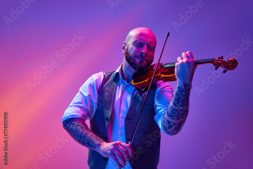 Принти на полотні Portrait of talented young man, solo performer playing violin against gradient purple background in neon light