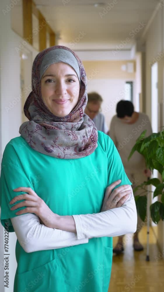 A female medical doctor or nurse wearing hijab standing proudly and smiles for the camera. Confident Muslim female doctor standing inside hospital A female medical doctor or nurse wearing hijab standing proudly and smiles for the camera. Confident Muslim female doctor standing inside hospital