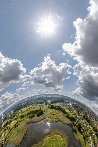 Aerial view from high altitude tiny planet in sky with clouds overlooking old town, urban development, buildings and crossroads. Transformation of spherical 360 panorama in abstract aerial view.