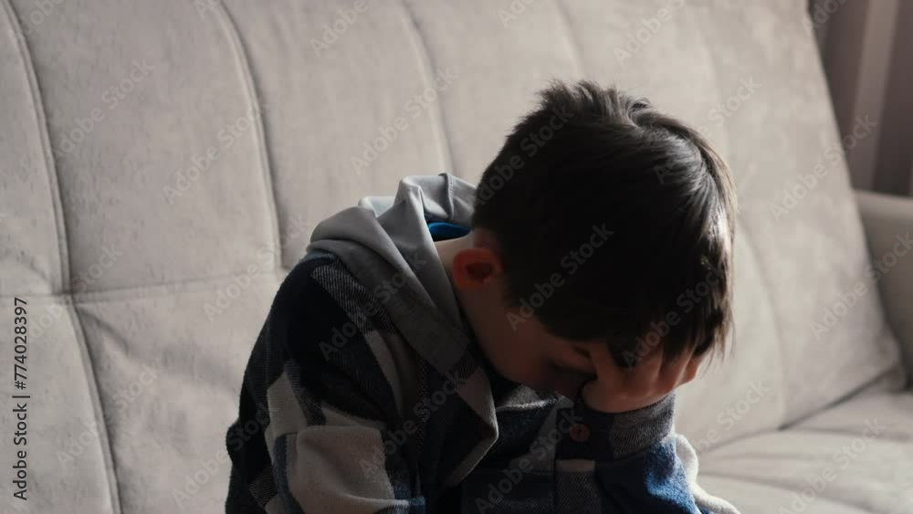 Teenage angst, moments of loneliness. the boy is sad at home sitting on the sofa holding his head with his hands. stress in a teenager's life Teenage angst, moments of loneliness. the boy is sad at home sitting on the sofa holding his head with his hands. stress in a teenager's life