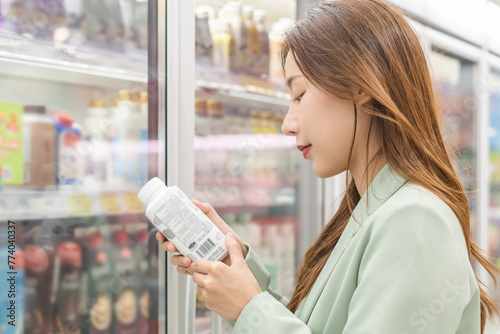 Foto Asian young woman in grocery, supermarket shopping food store hand holding bottl