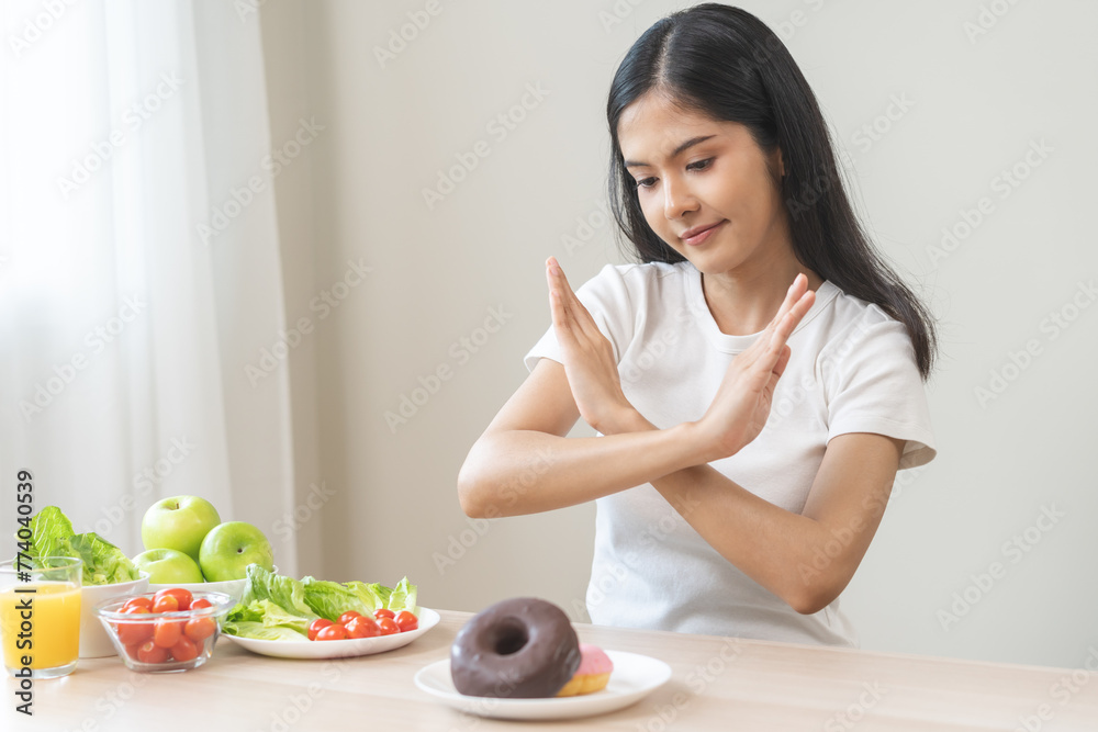 Diet, dieting asian young woman, girl hand push out, refuse, deny sweet donut, dessert doughnut on plate, choose green apple and vegetable salad, eat food for good healthy, female getting weight loss Diet, dieting asian young woman, girl hand push out, refuse, deny sweet donut, dessert doughnut on plate, choose green apple and vegetable salad, eat food for good healthy, female getting weight loss