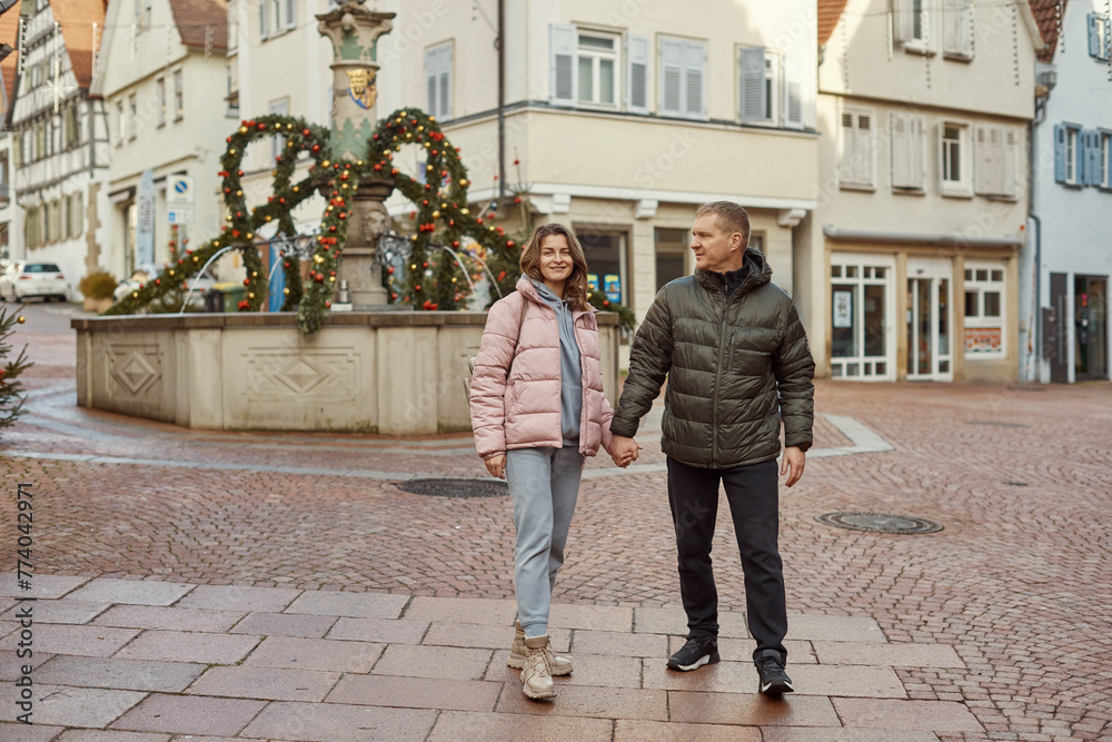Obraz premium Loving couple of tourists walking around old town. Couple of lovers leisurely stroll in the cool autumn morning on the streets of a BIETIGHEIM-BISSINGEN (Germany). The guy holds his wife. Vacation