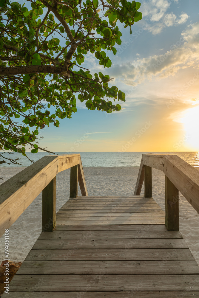 Wooden bridge on the sandy beach at sunset. Naples Beach, Florida