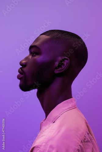 Artistic portrait of a man with a stylish ponytail in purple lighting