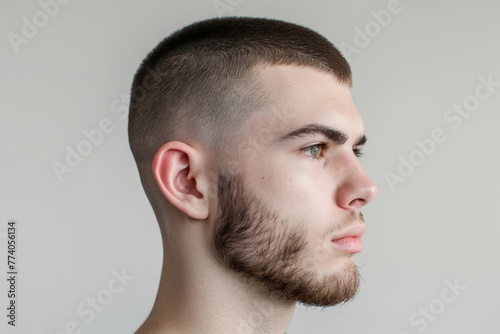 Close-up side view of a young man sporting a stylish textured crop haircut against a neutral background