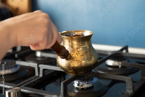 Close up shot of preparation of turkish coffee using copper cezve on the gas stove 