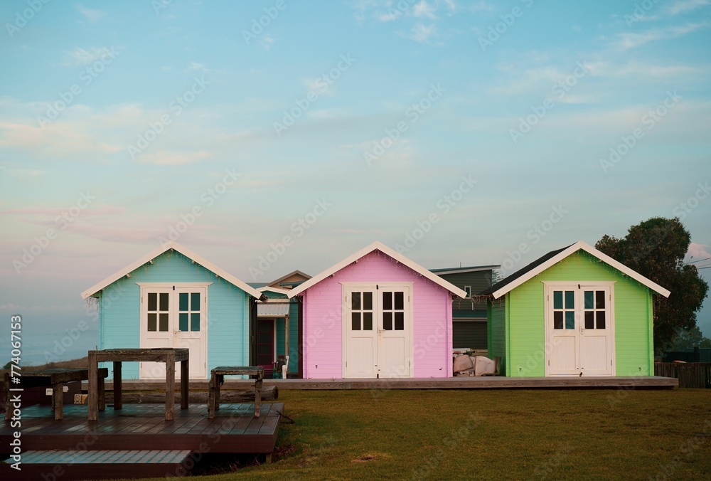 Row of cute colorful beach huts against blue cloudy sunset sky in New Zealand