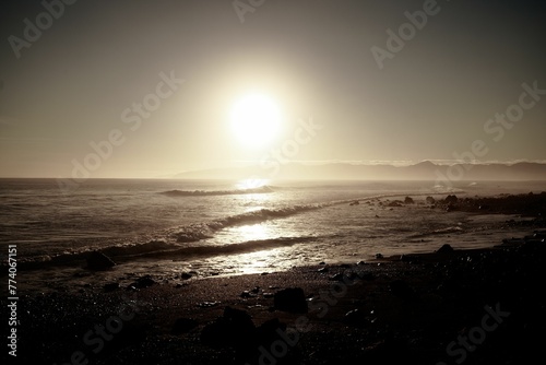 Bright blinding sun shining over the sea and Cape Palliser beach in New Zealand photo