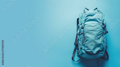 A grey backpack lying against a blue background with ample space for text