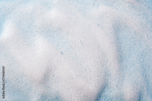 Cleaning sponge and a soapy foam on a blue background.