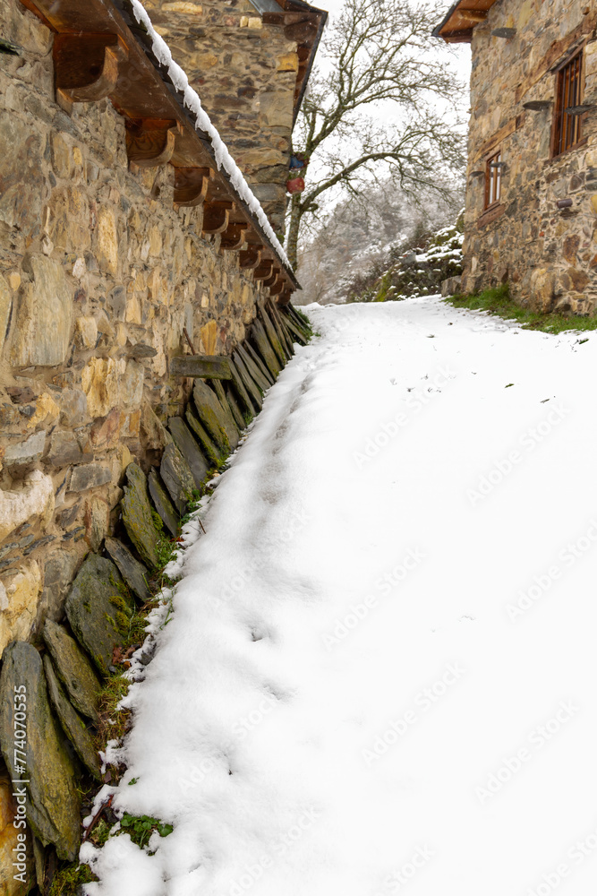 Fototapeta premium row of slate tiles stacked on the wall of a stone farmhouse in a snowy mountain village 