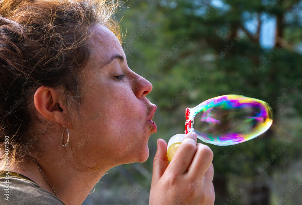 A pretty young woman plays with blowing soap bubbles on a sunny day
A pretty young woman plays with blowing soap bubbles on a sunny day