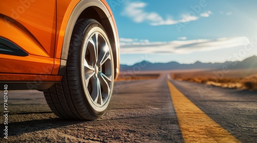 Close-up of the wheels and tires of an orange car on a receding empty road in the Colorado desert © Vadim