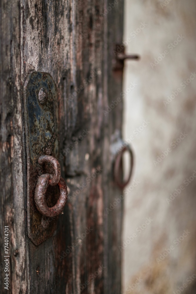 Vertical closeup of a wooden gate with a rusty metal handle