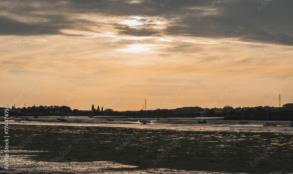 Fototapeta premium Boats on the seaside at sunset with an orange cloudy sky in the background