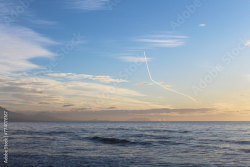 a trail of an airplane in the sky above the sea