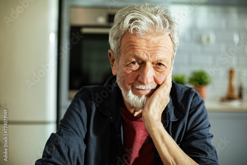 Portrait of a smiling elderly man with a beard in a home kitchen photo
