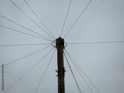 Low-angle shot of a telecommunications pole with wires on a cloudy day