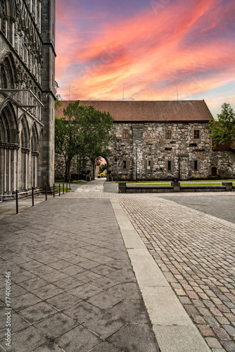 Sunset Glow at Archbishops Palace and Nidaros Cathedral in Trondheim, Norway. The fading evening sky casts warm hues over the cobblestone square of the Cathedral and the Palace of Norwegian Landmark photo