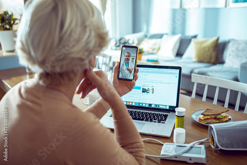 Elderly woman in telehealth session with doctor on smartphone at home photo