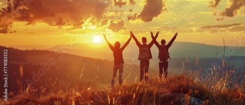 A group of very happy friends stands with their arms raised and enjoys the sunset at sunset mountain