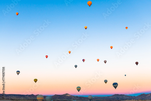 Colorful hot air balloons flying over the mountains in Cappadocia, Turkey.