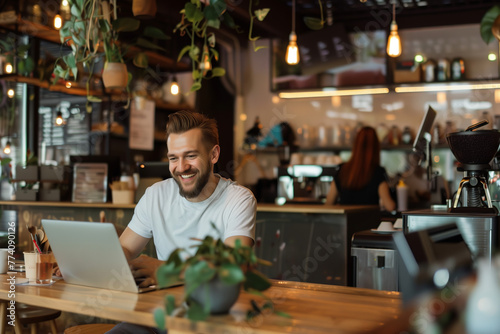 Happy man working online at a modern cafe with laptop