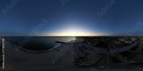 Panoramic shot of the beach coastline under a beautiful sunset sky with the city view photo