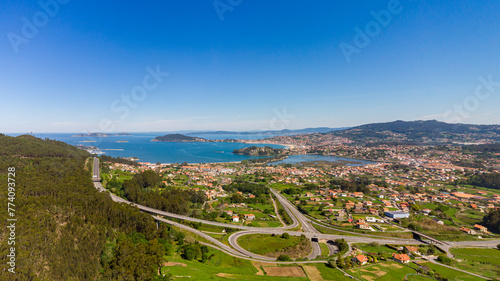 Aerial panorama of the surroundings of Baiona (Galcia). The highway in the foreground, Baoina beach, the mouth of the Miñor River, Monte Lourido and the Cíes Islands in the background