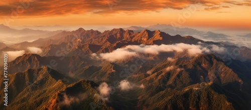 Aerial view of mountains in orange clouds at sunset in summer.