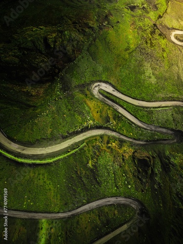 Birds eye view shot of a serpentine road leading through mountain landscape