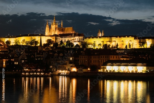 Beautiful scenery of illuminated Prague Castle at night reflected on the Vltava river © Wirestock