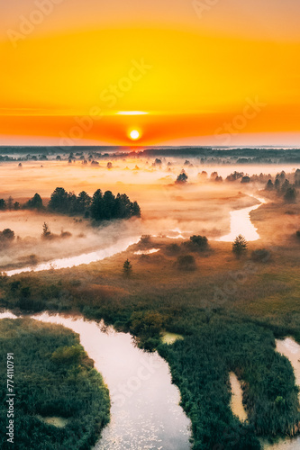 Aerial Elevated View Green Meadow And River Landscape In Misty Foggy Morning. Top View Of Beautiful European Nature From High Attitude In Summer Season. Drone View. Bird's Eye View. © Grigory Bruev