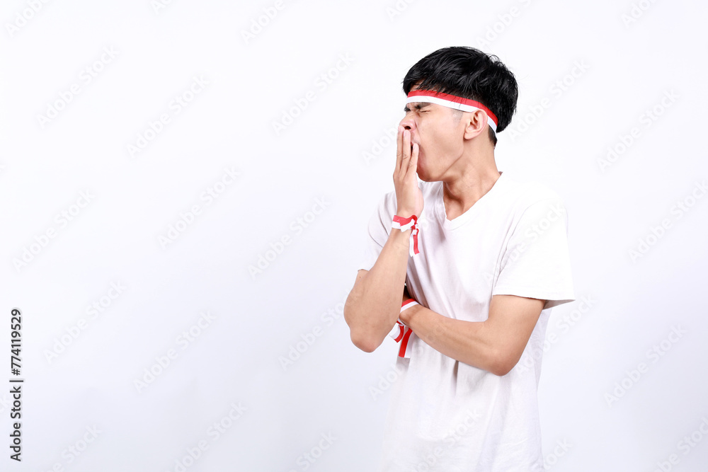 Sleepy Young asian boy with red white ribbon celebrating Indonesia independence day while yawning Sleepy Young asian boy with red white ribbon celebrating Indonesia independence day while yawning