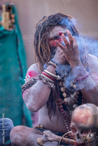 Portrait of an naga aghori sadhu holy man with pyre ash on his face and body smoking chilam at harishchandra ghat in varanasi.	 photo