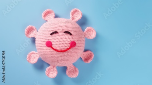 Knitted, cute pink sun with a smile on a blue background, top view, with space for text. Greeting card, hobbies, knitting, children's toys. © Cherkasova Alie