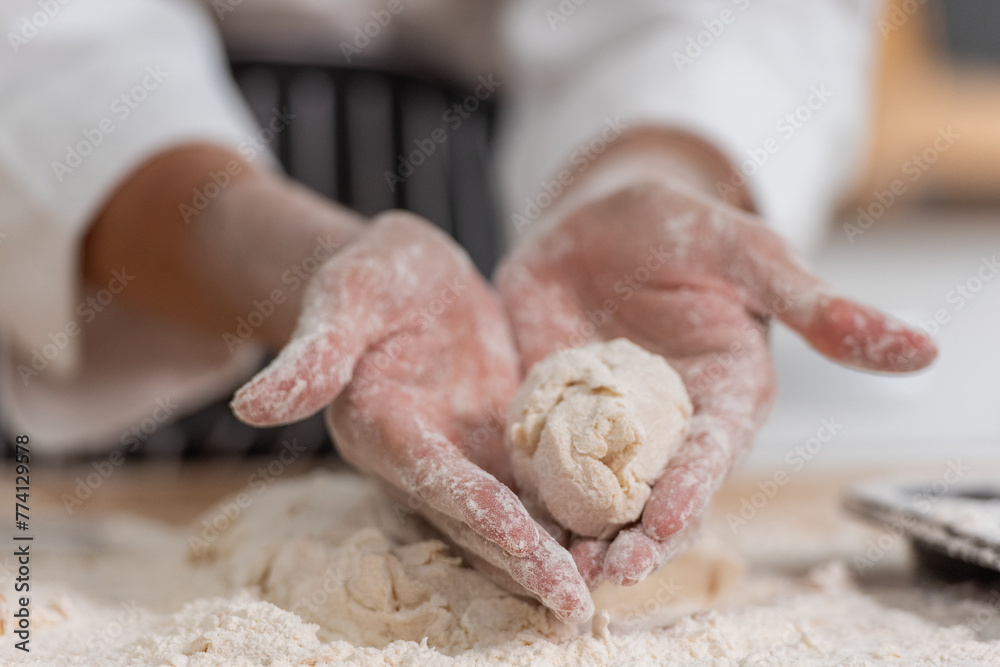 professional Chef sifting flour powder and sprinkling ingredients on massaging dough for bakery cooking. Chef show dirty finger hand sifting flour wheat and kneading dough mixing powder.