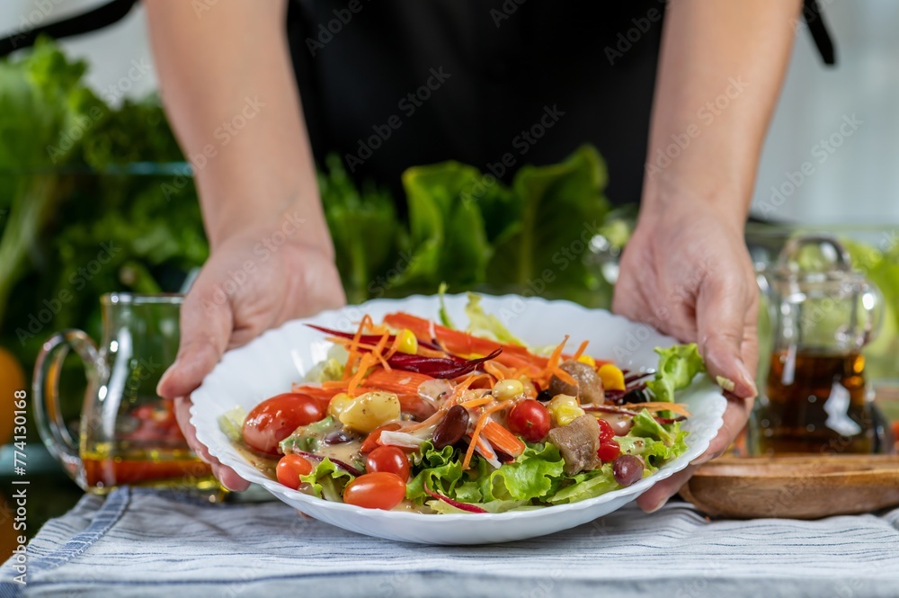 woman chef show mix fresh green baby cos salad and pour salad dressing in glass blow. Organic Vegetables mix all green salad In glass bowl. Breakfast fresh salad and clean vegetable.