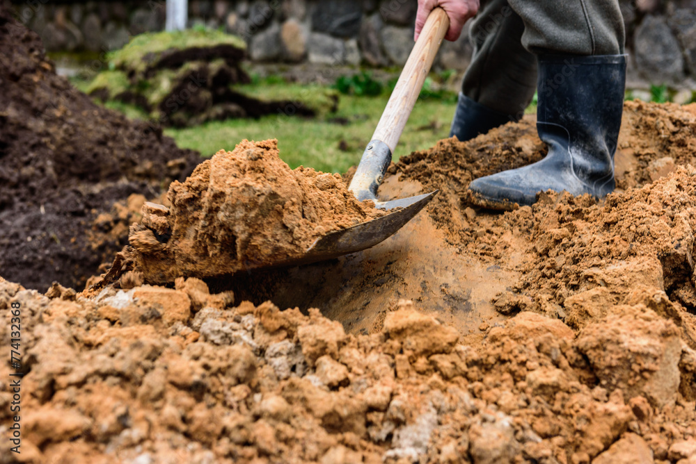 Earthworks, man digging trench using shovel. Earthworks, man digging trench using shovel.