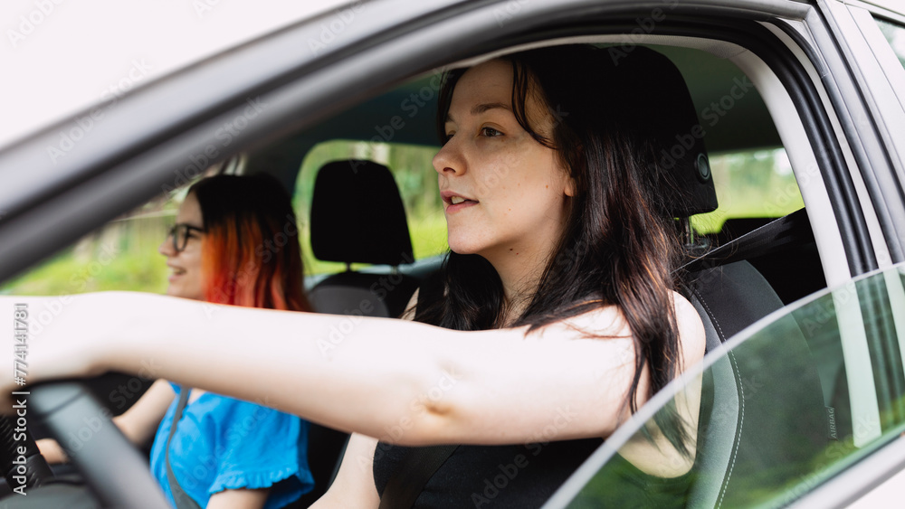 Naklejka premium Two girls happily travel by car, one of them driving, during a weekend getaway
