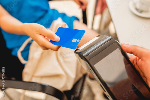 A young girl pays with a contactless credit card on a pos payment terminal after having a coffee