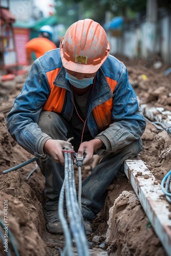 Electrical Cable Connection by Worker in Trench © Tadeusz