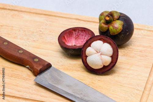 Queen of fruit. Mangosteens and knife on the wooden plate.