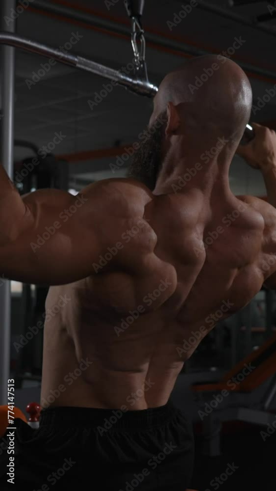 Caucasian man doing lat pull-downs on a machine. Vertical video. Caucasian man doing lat pull-downs on a machine. Vertical video.